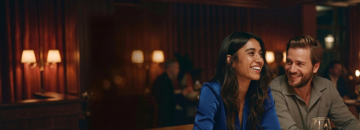 A woman in a blue silk blouse laughing at something her partner said at a candlelit restaurant
